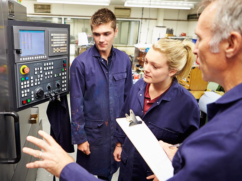 Engineer Teaching Apprentices To Use Computerized Lathe